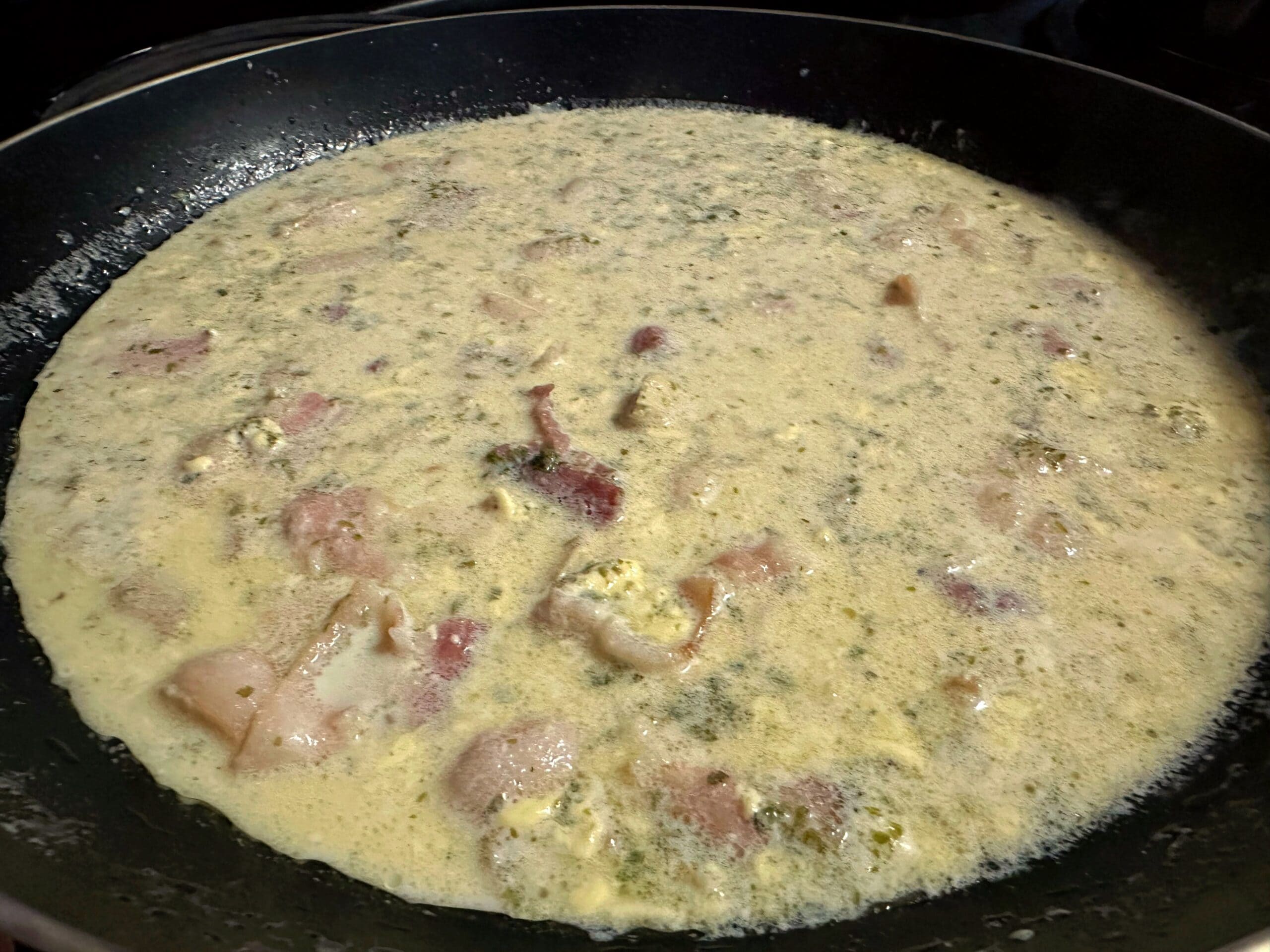 青のりとツナ、ベーコンを加えた和風クリームソースをフライパンで煮込んでいる様子