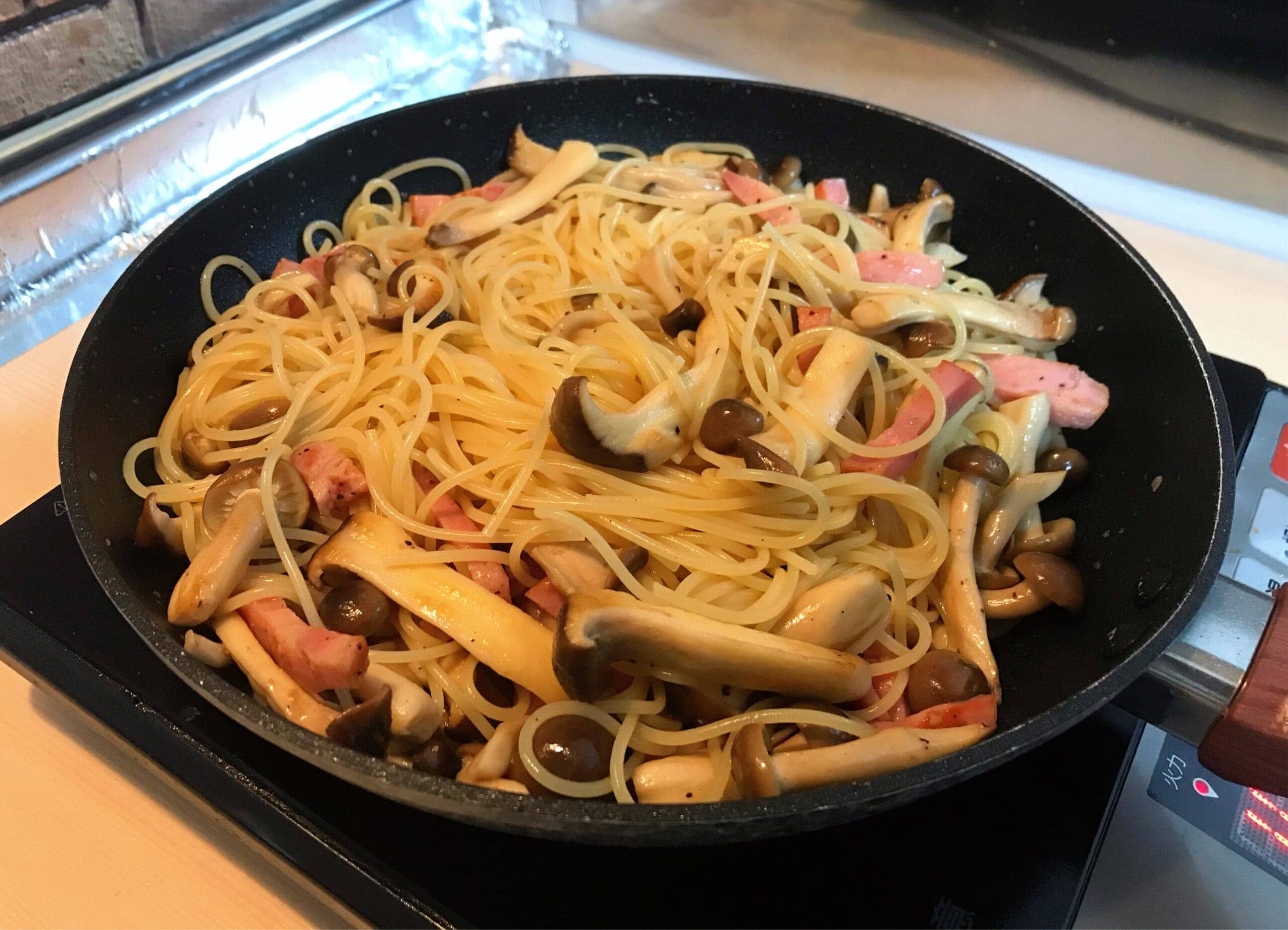 フライパンでベーコンときのこを炒めて作る和風パスタの調理中写真。簡単に作れる時短パスタレシピ