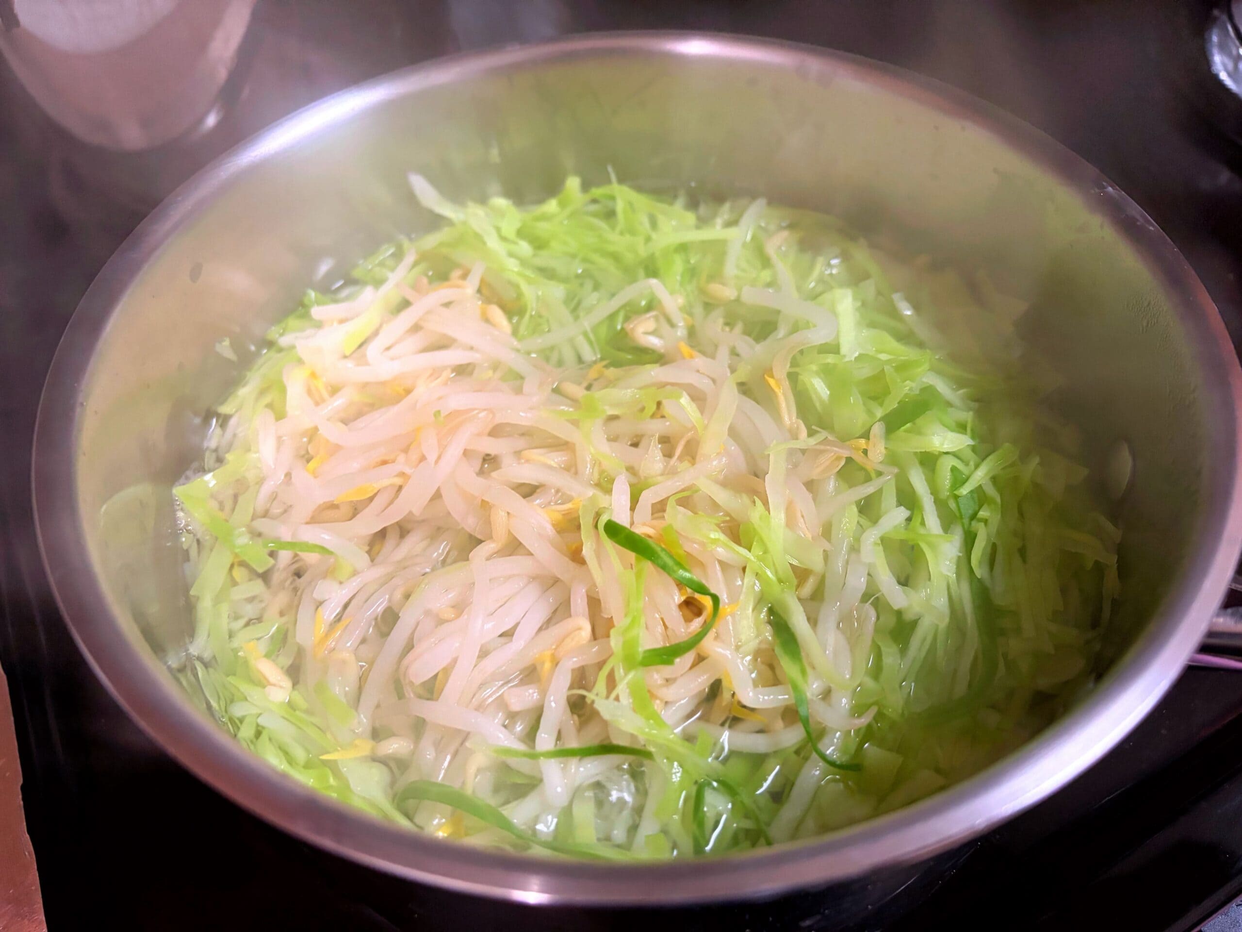 鍋でキャベツともやしをさっと茹で、食べやすくする下処理の様子
