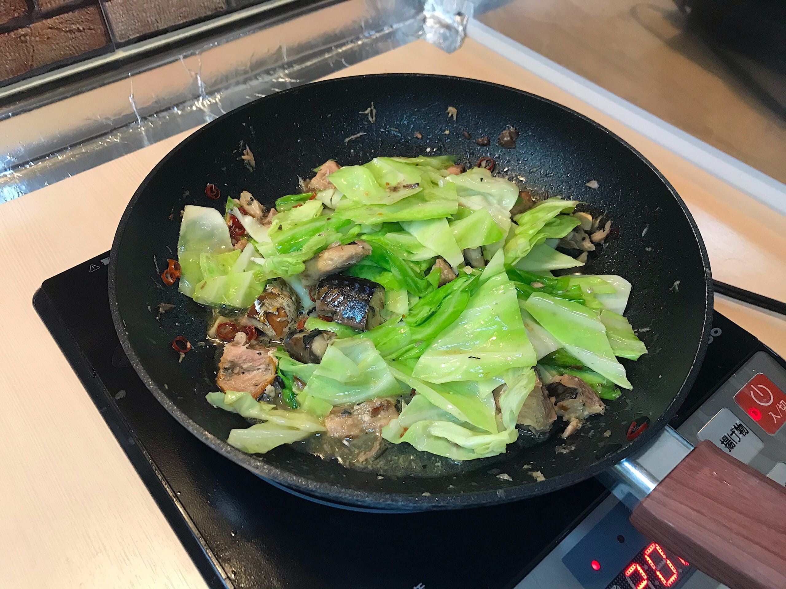 フライパンでキャベツと鯖缶を炒め、にんにくと唐辛子を加えたペペロンチーノの調理工程