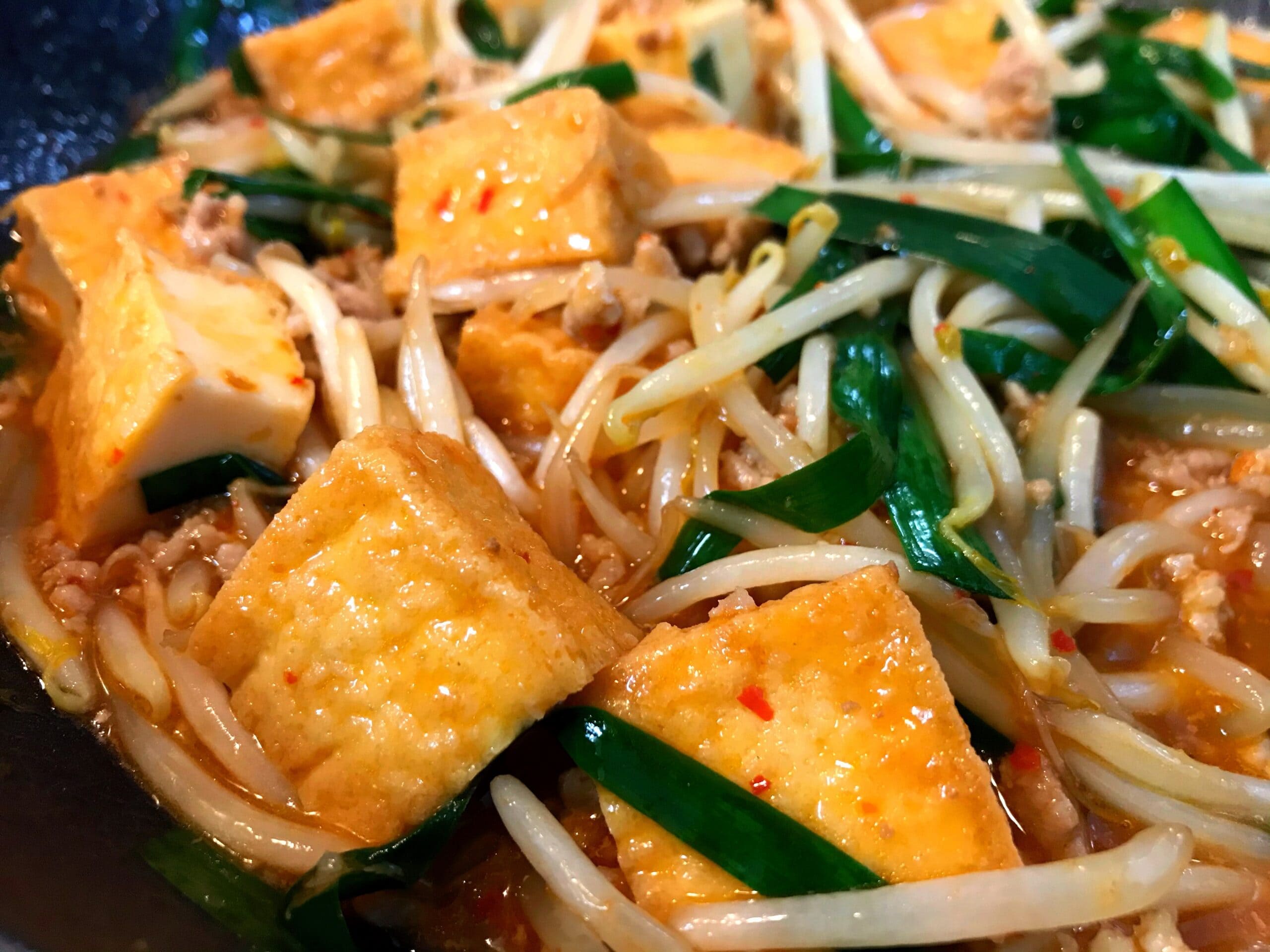 フライパンでもやしと厚揚げをピリ辛ダレで炒めている調理中の写真