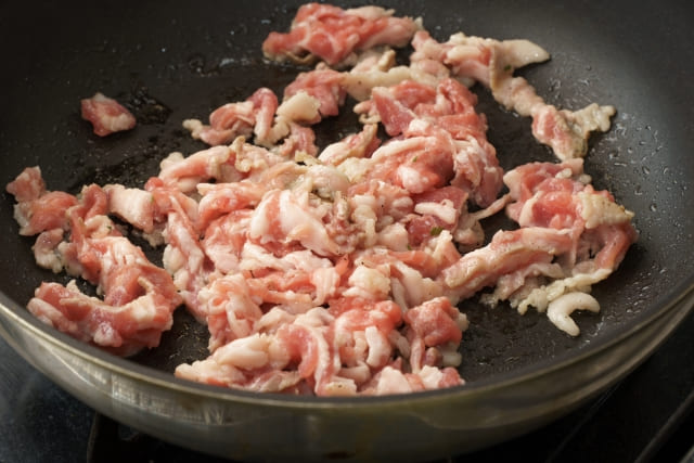 フライパンで豚肉を最初に焼いて旨みを出している中華炒めの調理工程写真