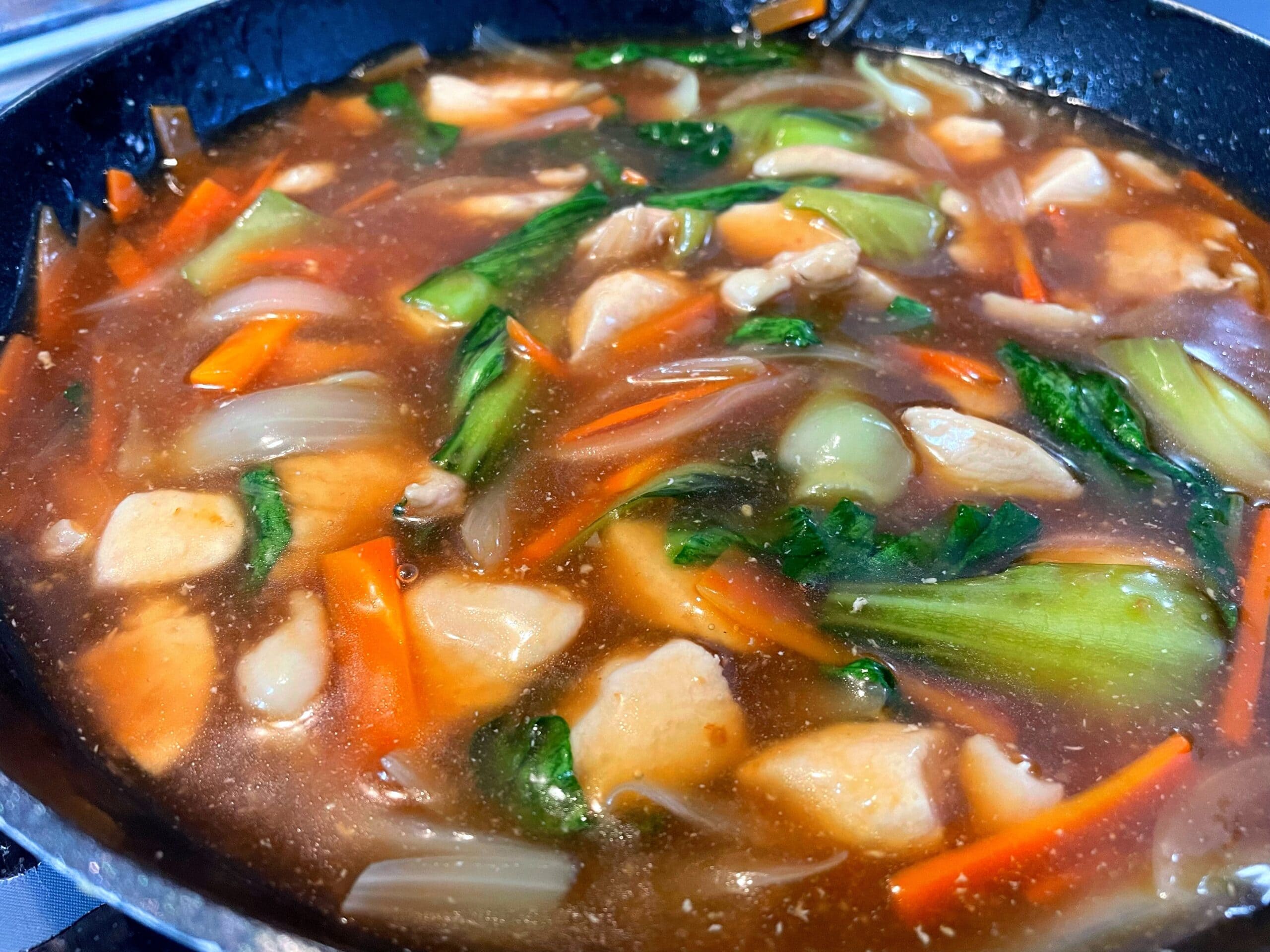 チンゲン菜と鶏肉の中華あんかけうどんをフライパンで調理している様子