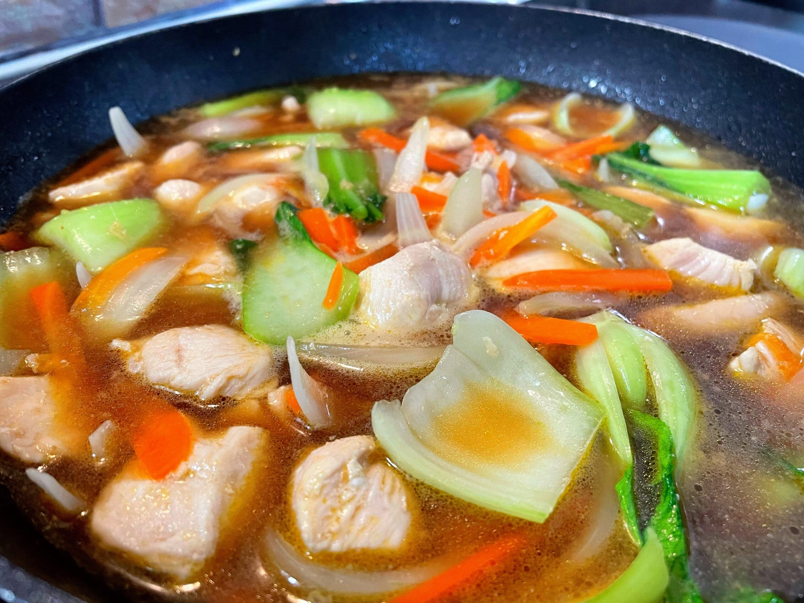 チンゲン菜と鶏肉を使った中華あんかけうどんの具材を煮ている写真