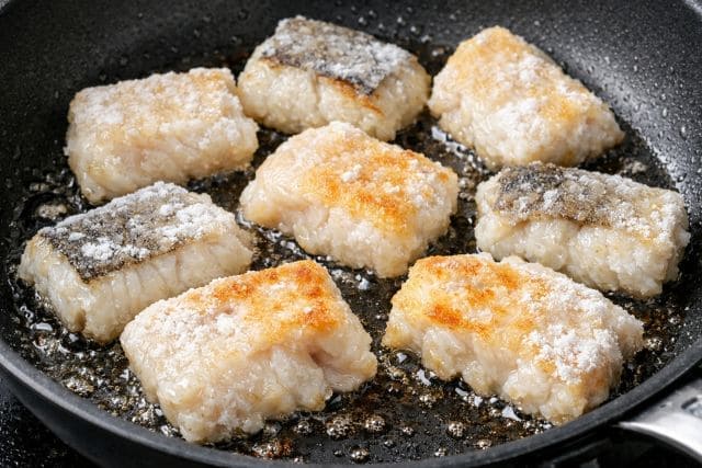 フライパンで白身魚の切り身を焼いている魚料理の調理工程
