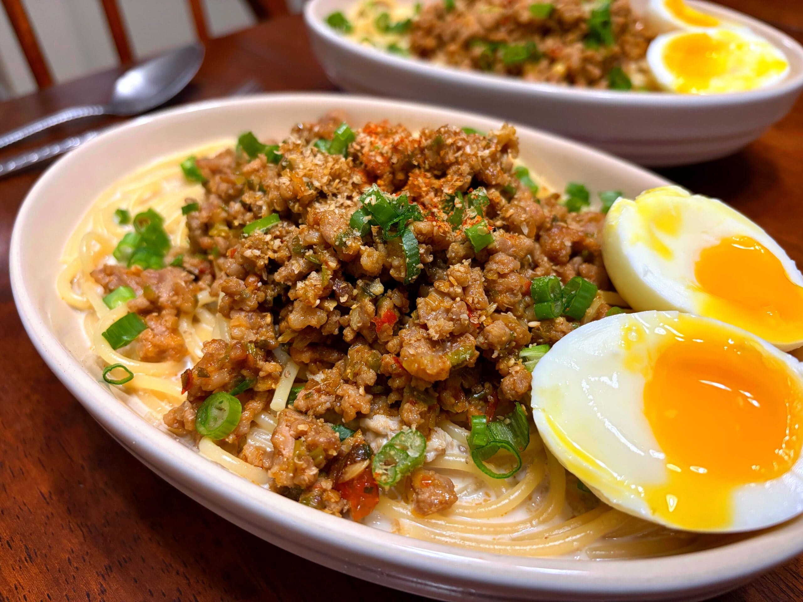 挽き肉たっぷりの濃厚ピリ辛坦々風胡麻ミルクスープパスタの完成写真。半熟卵とネギをトッピングした簡単レシピ