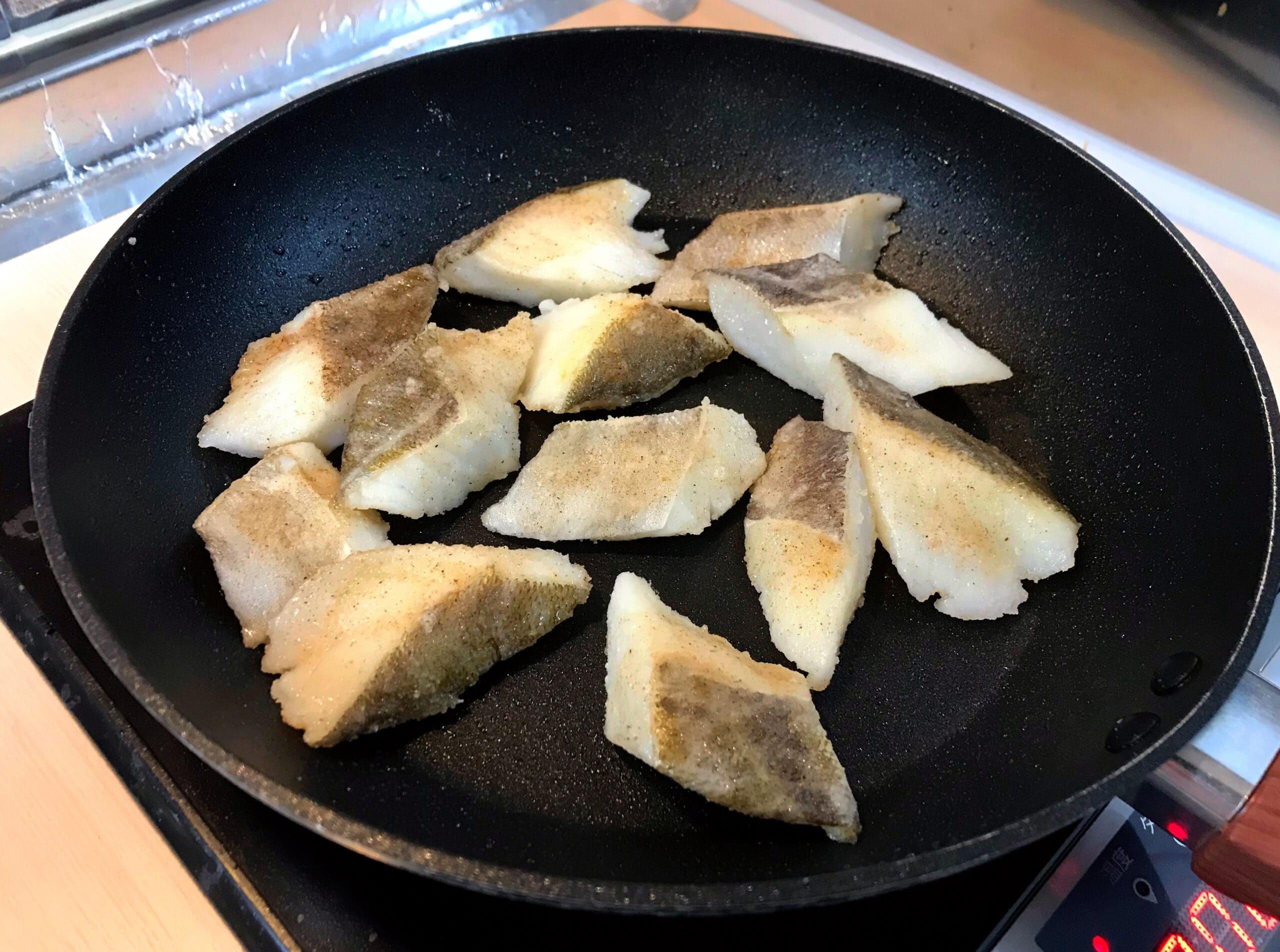 片栗粉をまぶした鱈の切り身をフライパンで焼いている様子