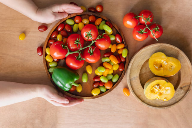 トマトとカラフルなミニトマトを木皿に並べた野菜料理のイメージ