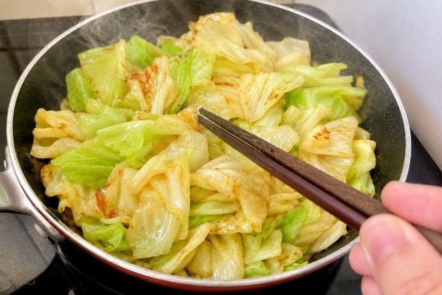 フライパンでキャベツを炒め、甘みと香ばしさを引き出している調理途中の写真