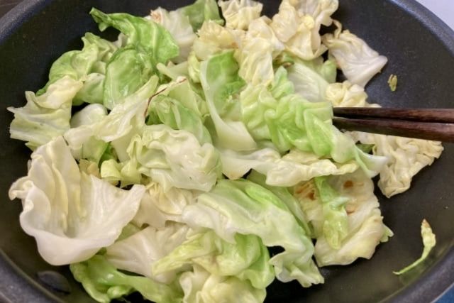 キャベツをフライパンでさっと炒めている写真