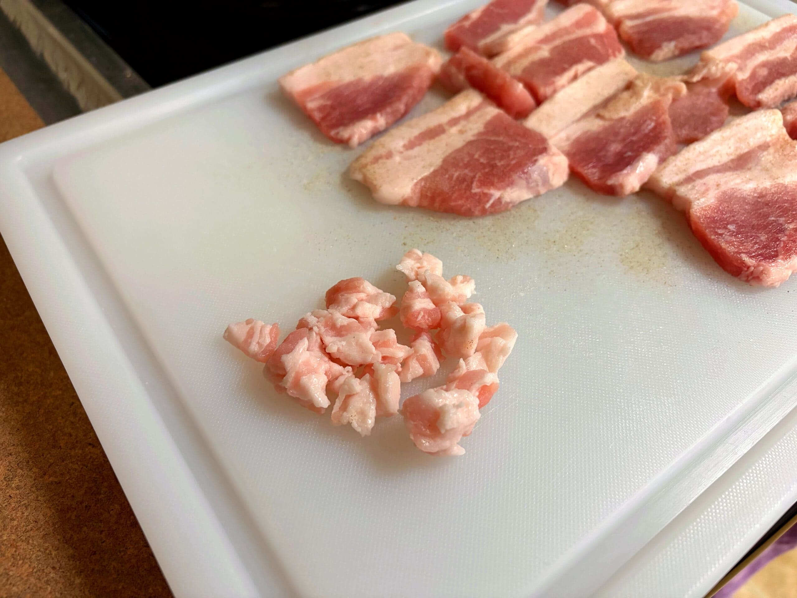 豚ニンニク醤油の野菜マシマシ二郎パスタ用に、豚バラ肉の脂身を切り分けて細かく刻んでいる写真