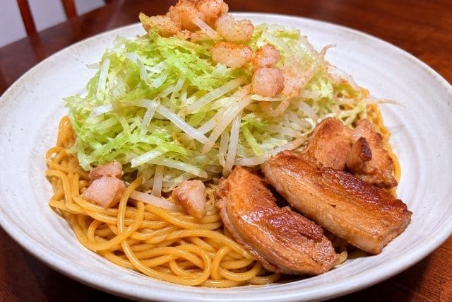 豚ニンニク醤油の野菜マシマシ二郎パスタを、豚肉ともやし、キャベツをたっぷりのせて盛り付けた写真