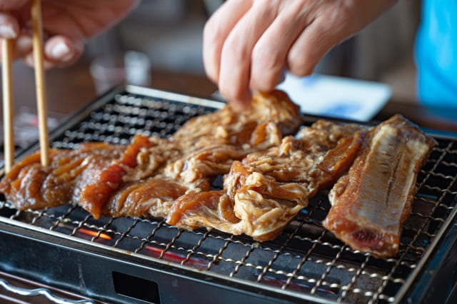 特製タレに漬け込んだLAカルビを網の上で香ばしく焼いている韓国風焼肉の写真