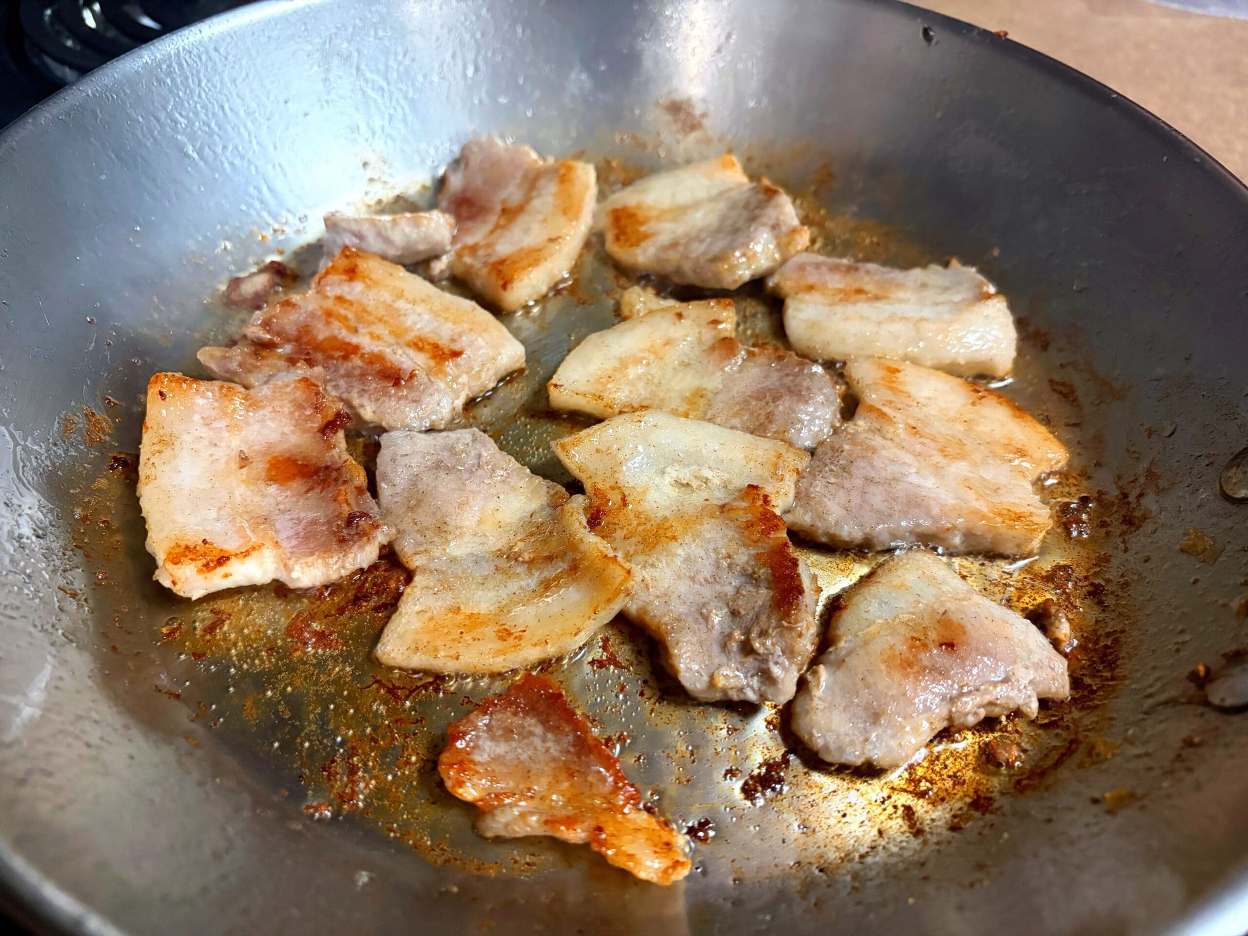豚ニンニク醤油の野菜マシマシ二郎パスタ用に、豚バラ肉をフライパンで焼いて香ばしい焼き目をつけている写真