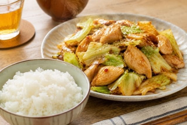 白ごはんと一緒に盛り付けた、鶏むね肉とキャベツのピリ辛炒めの節約おかず写真