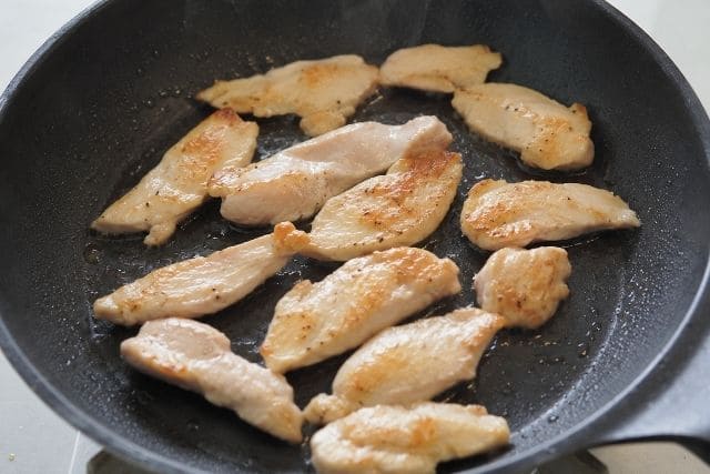 そぎ切りにした鶏むね肉をフライパンで焼き色がつくまで炒めている写真