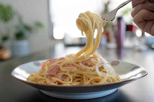 ツナとベーコンを使った青のり入り和風クリームパスタをフォークで持ち上げた写真。おうちで作れる簡単パスタレシピ