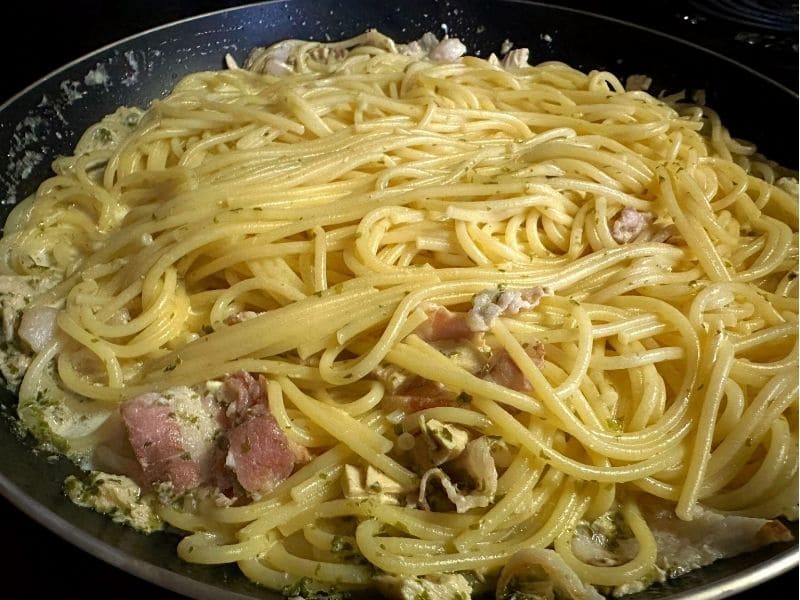 茹でたパスタをフライパンに入れ、青のりとツナベーコンの和風クリームソースを絡めて仕上げている調理途中の写真