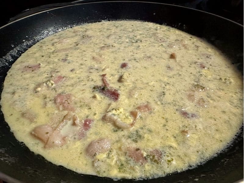 フライパンでベーコンとツナ缶、牛乳、和風だし、青のりを温めて和風クリームソースを作っている調理途中の写真