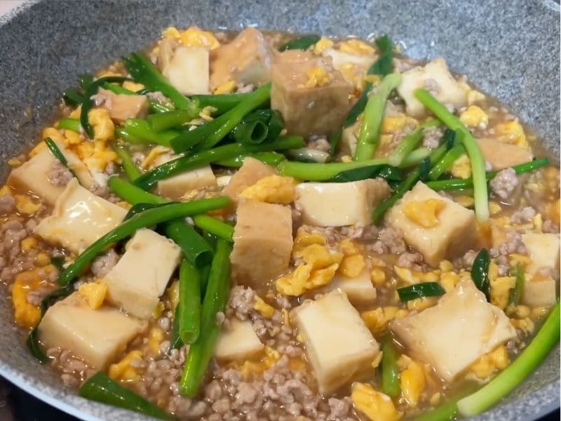 厚揚げ、豚ひき肉、卵そぼろ、万能ねぎを甘辛い煮汁で煮込んでいる厚揚げのネギ玉そぼろあんかけ丼の調理途中