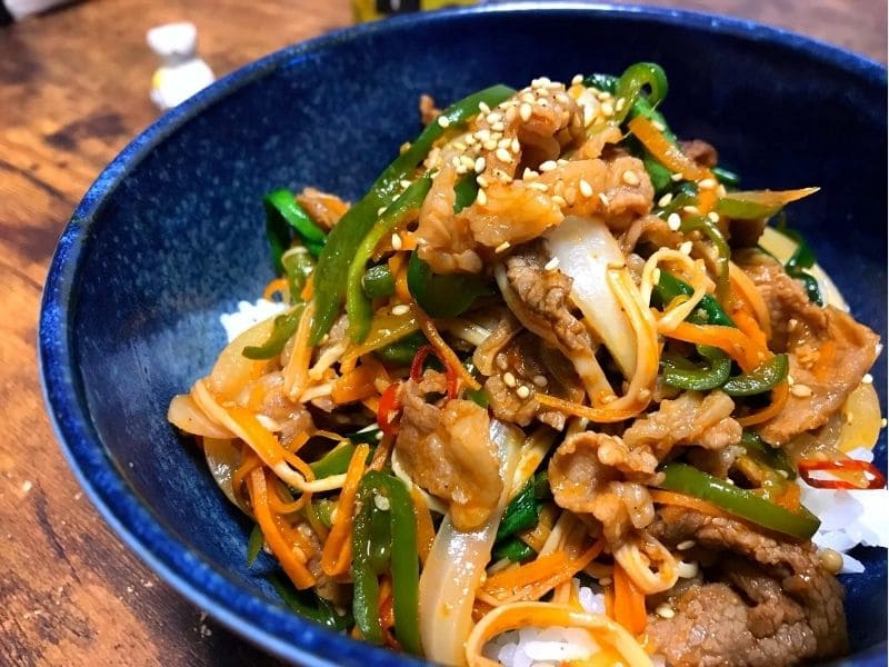 牛こま切れとニンジン、ピーマン、玉ねぎ、エノキ、ニラを甘辛く炒めてご飯にのせたプルコギ丼