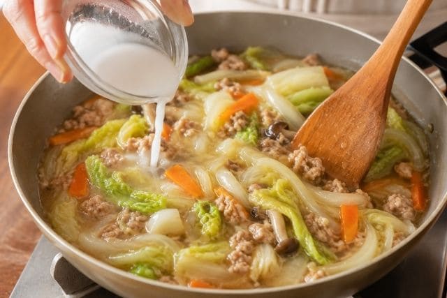 豚ひき肉と野菜のあんに水溶き片栗粉を加えてとろみを付けている様子