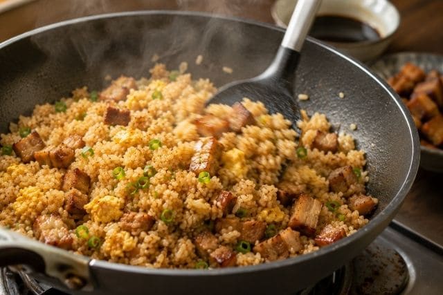 フライパンで豚の角煮チャーハンを手早く炒め、パラッと仕上げている調理工程