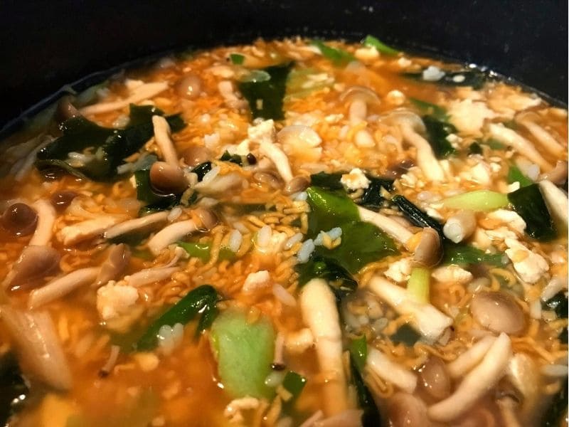 鍋で鶏ひき肉、しめじ、わかめ、チキンラーメン、ごはんを煮込んでいるチキンラーメン雑炊の調理工程