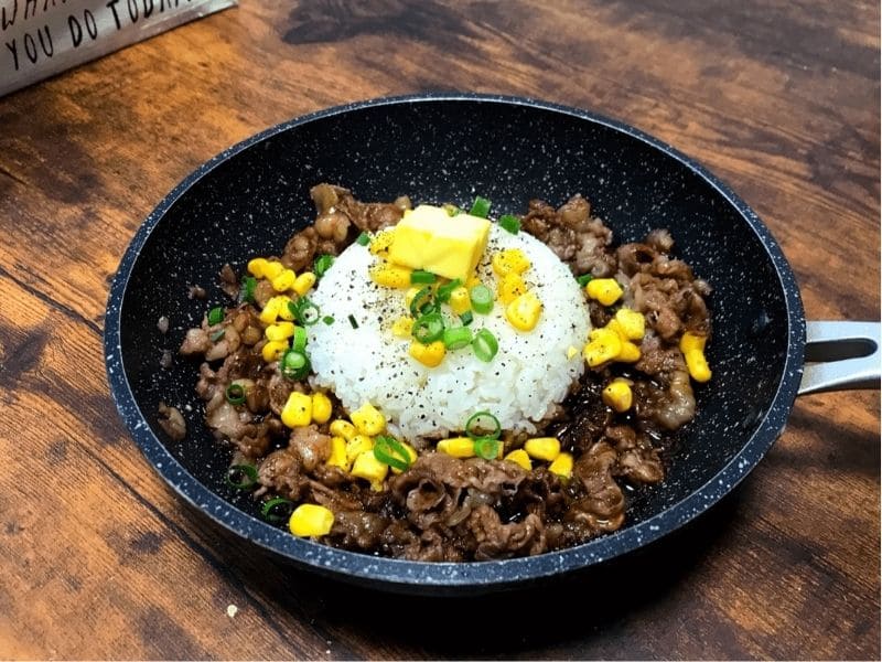 フライパンで作ったビーフペッパーライス。中央に丸く盛ったご飯にバターをのせ、周りに牛肉、コーン、小ネギを盛り付けた完成写真。