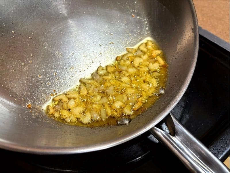 豚ニンニク醤油の野菜マシマシ二郎パスタ用に、オリーブオイルで刻みにんにくと豚肉の脂身をじっくり炒めて香りを引き出している写真