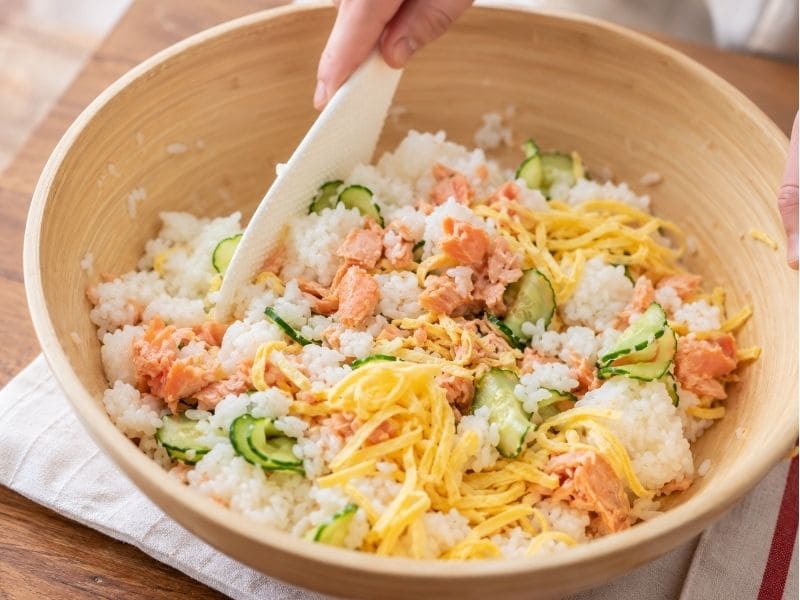 酢飯に鮭フレーク、塩抜きしたきゅうり、錦糸卵を加えて混ぜ合わせる調理途中の写真