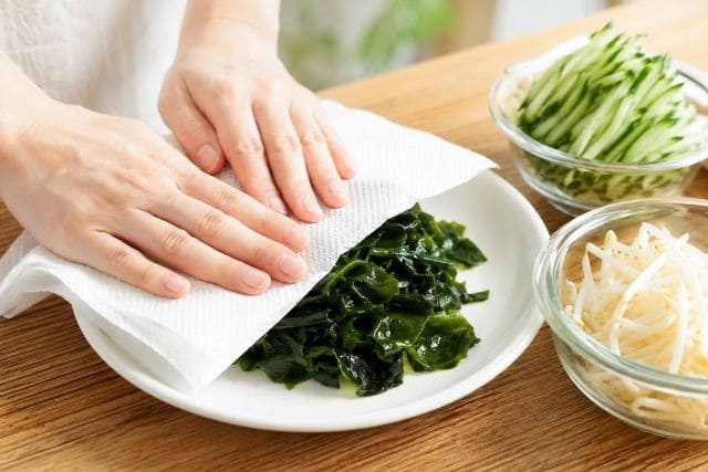 きゅうりとわかめのもやしナムル用に、戻したわかめの水気をキッチンペーパーで取っている様子。