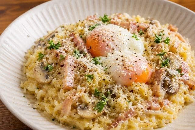 カルボナーラ風チキラー飯に温泉卵、パルメザンチーズ、黒コショウ、パセリをのせた完成写真