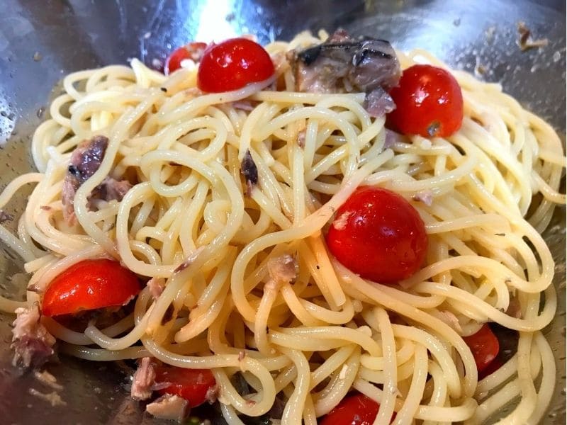 冷やしたパスタに鯖缶とミニトマトを加えてボウルで混ぜ合わせている調理途中の写真