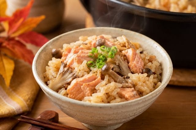 鮭とキノコのバター醤油炊き込みご飯を器に盛り付けた秋らしい写真