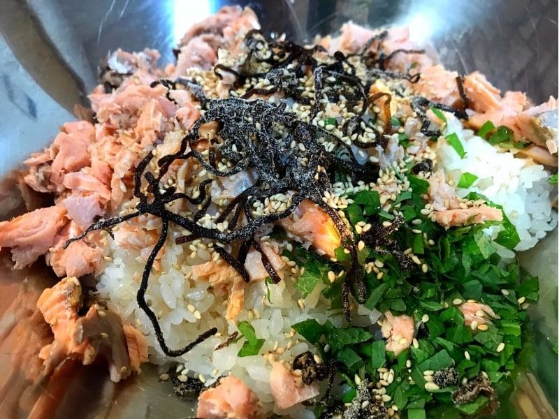 ボウルにご飯、ほぐした塩鮭、刻んだ大葉、塩こんぶを入れて混ぜ合わせる様子