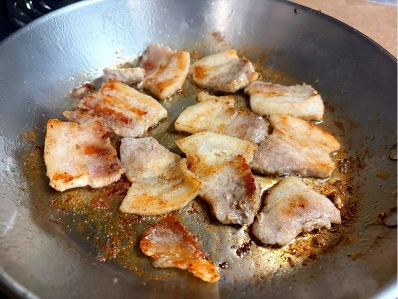 豚ニンニク醤油の野菜マシマシ二郎パスタ用に、豚バラ肉をフライパンで焼いて香ばしい焼き目をつけている写真