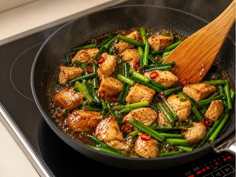 フライパンで鶏むね肉とニラをタレで炒めているスタミナ照り焼きの調理途中