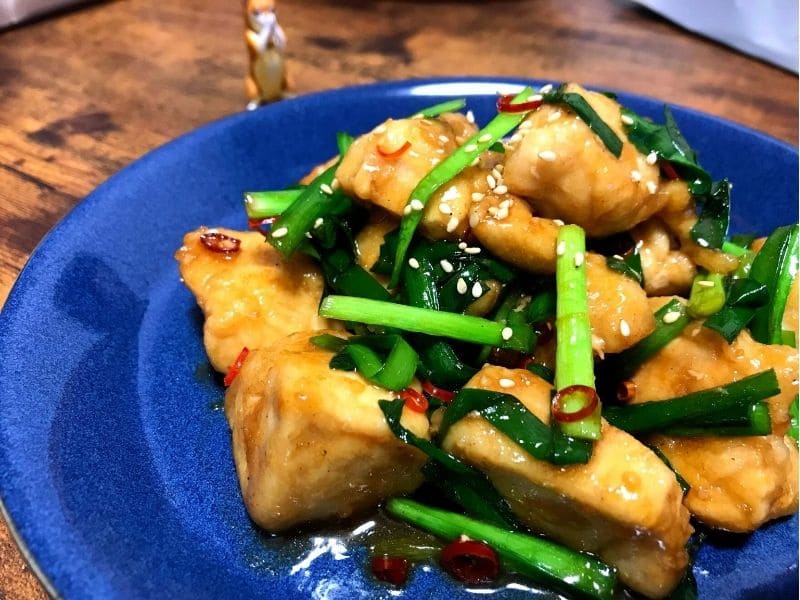青い皿に盛り付けた鶏むね肉とニラのスタミナ照り焼き