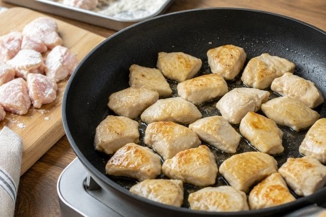 片栗粉をまぶした鶏むね肉をフライパンで焼いている調理工程