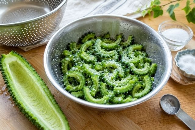 薄切りにしたゴーヤに塩と砂糖をなじませて苦味を抑える下ごしらえ