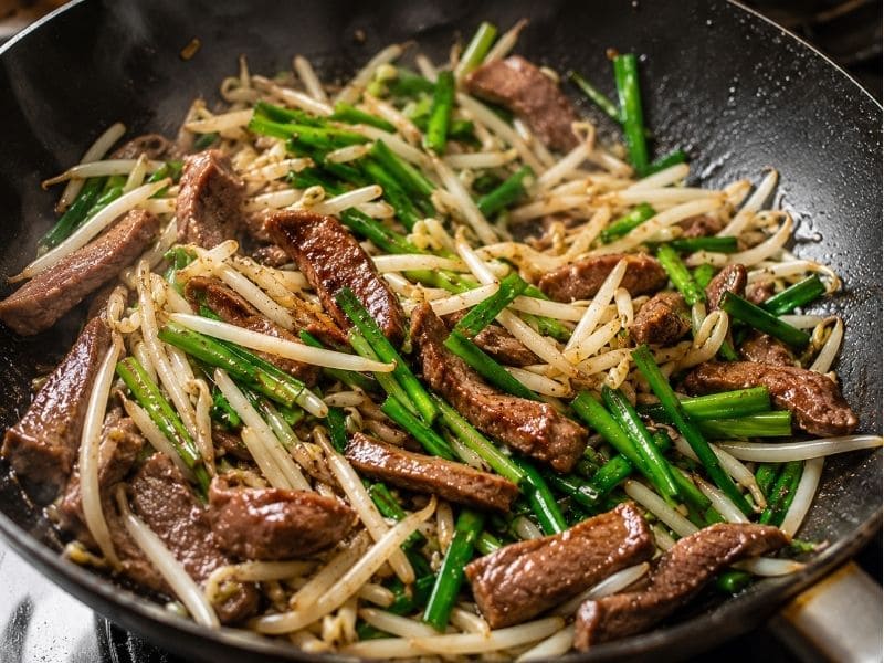 フライパンで牛タンともやしとニラを強火で炒めている調理工程