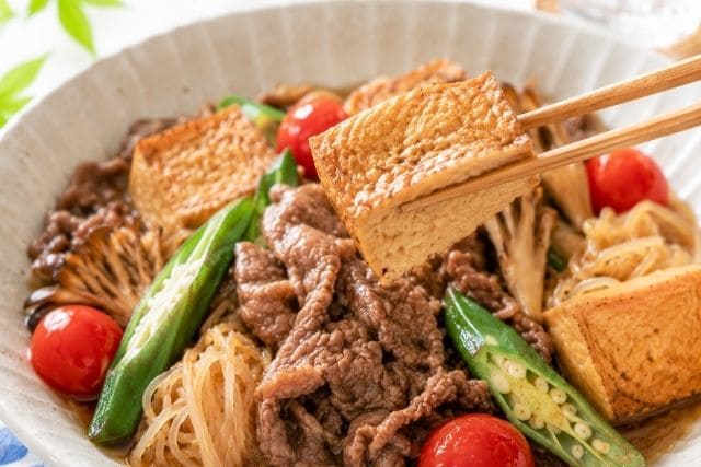 甘辛だれがしみた厚揚げを箸で持ち上げた夏野菜の冷やし牛すき焼き