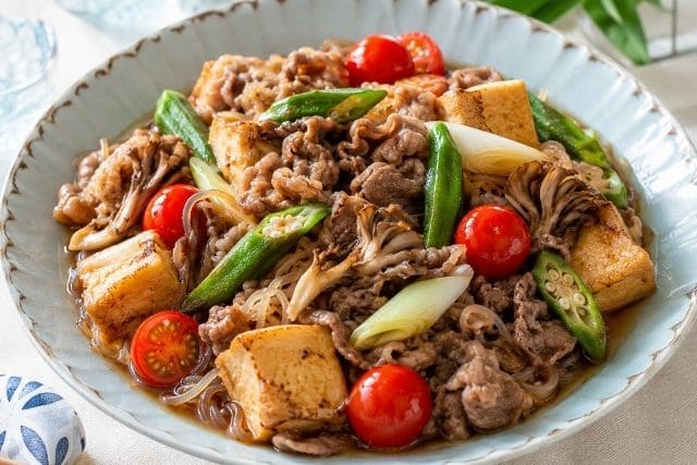 牛薄切り肉、厚揚げ、オクラ、ミニトマト、舞茸、糸こんにゃくを盛り付けた夏野菜の冷やし牛すき焼き