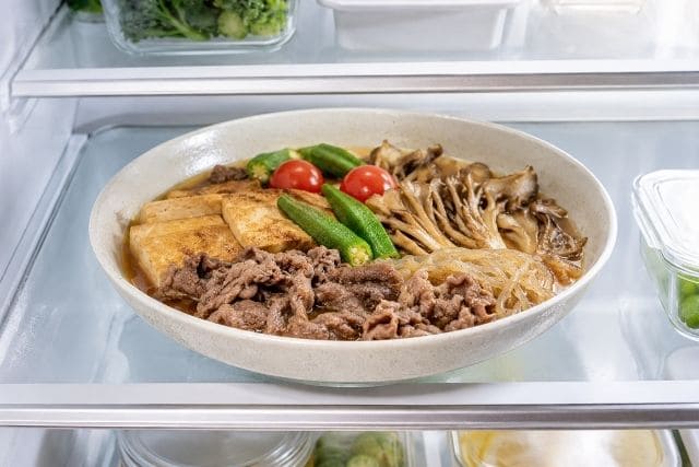 牛肉、厚揚げ、糸こんにゃく、舞茸を甘辛だれで煮た夏野菜の冷やし牛すき焼きを冷蔵庫で冷やしている写真