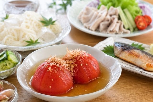 白だしに漬けた湯むきトマトにカツオ節と白ごまをのせた冷やしトマトおでん