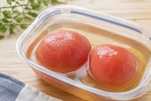 湯むきしたトマトを白だしに漬けて味をしみ込ませる冷やしトマトおでんの工程写真