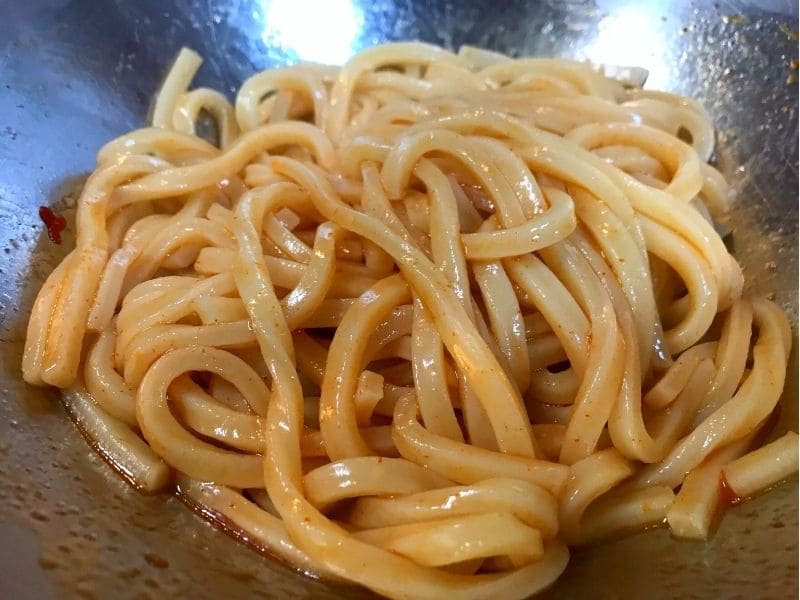 酢、醤油、ごま油、砂糖、コチュジャンのピリ辛だれを冷凍うどんに絡めた様子
