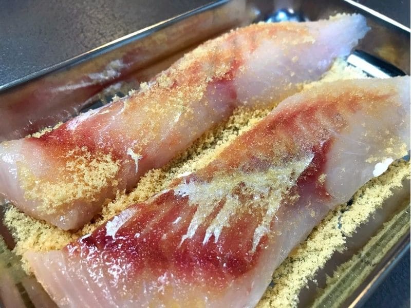タラの切り身全体に砂糖をまぶして臭み取りをしている様子