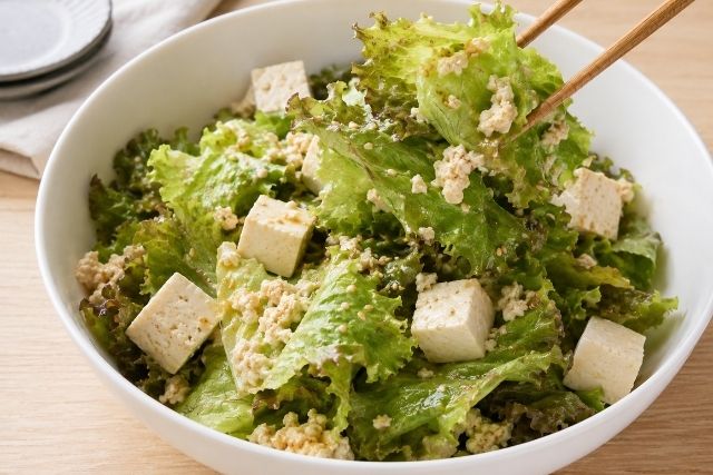 木綿豆腐の半量を軽く崩しながらサニーレタスとやさしく和える様子